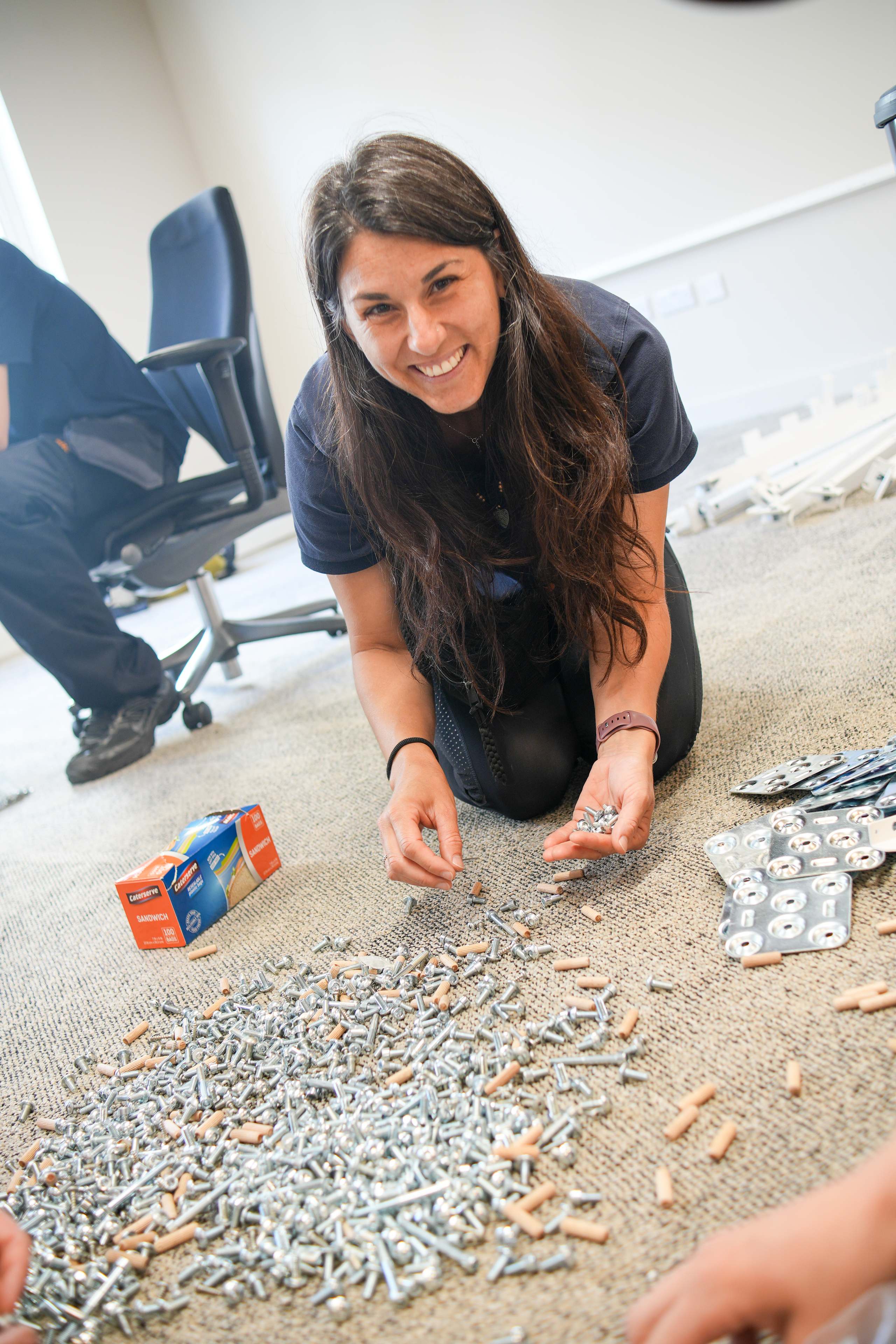 Painless Removals team member sorting and tracking office desk fixings during reassembly at a Bristol office