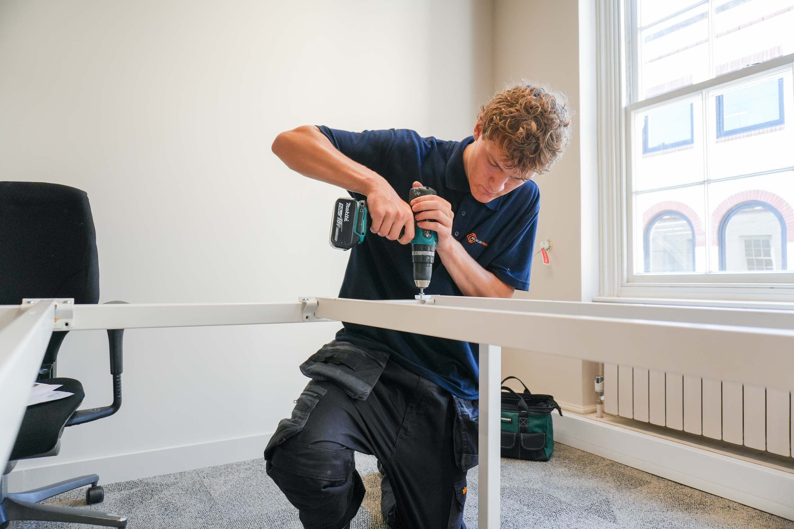 Painless Removals team member reassembling an office desk frame at a Bristol business relocation